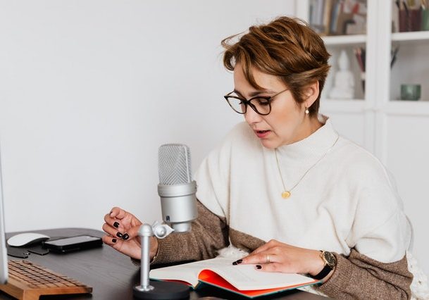 woman narrating story while recording audiobook